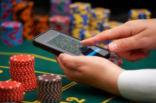 Finger som dras över skärm på en smartphone över ett roulettebord med spelmarker